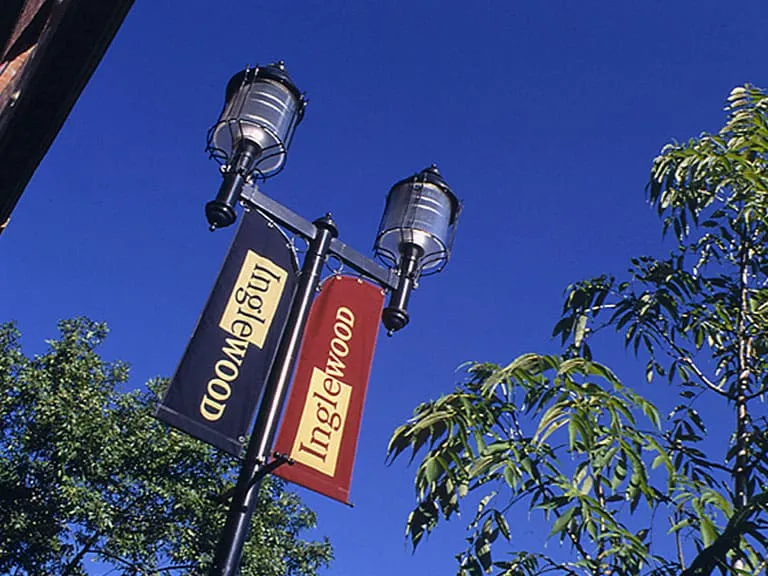 Street lamps with red Inglewood banners against a deep blue sky