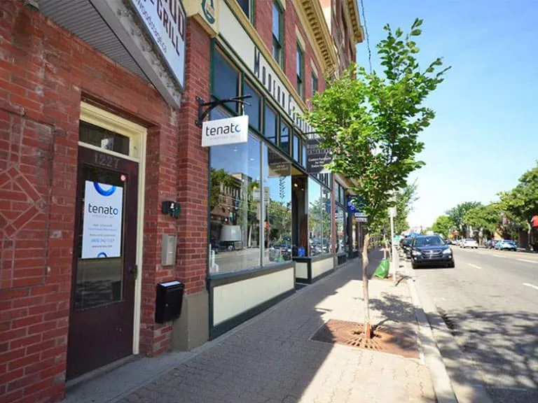A brick storefront and tree-lined sidewalk on a sunny day in Inglewood